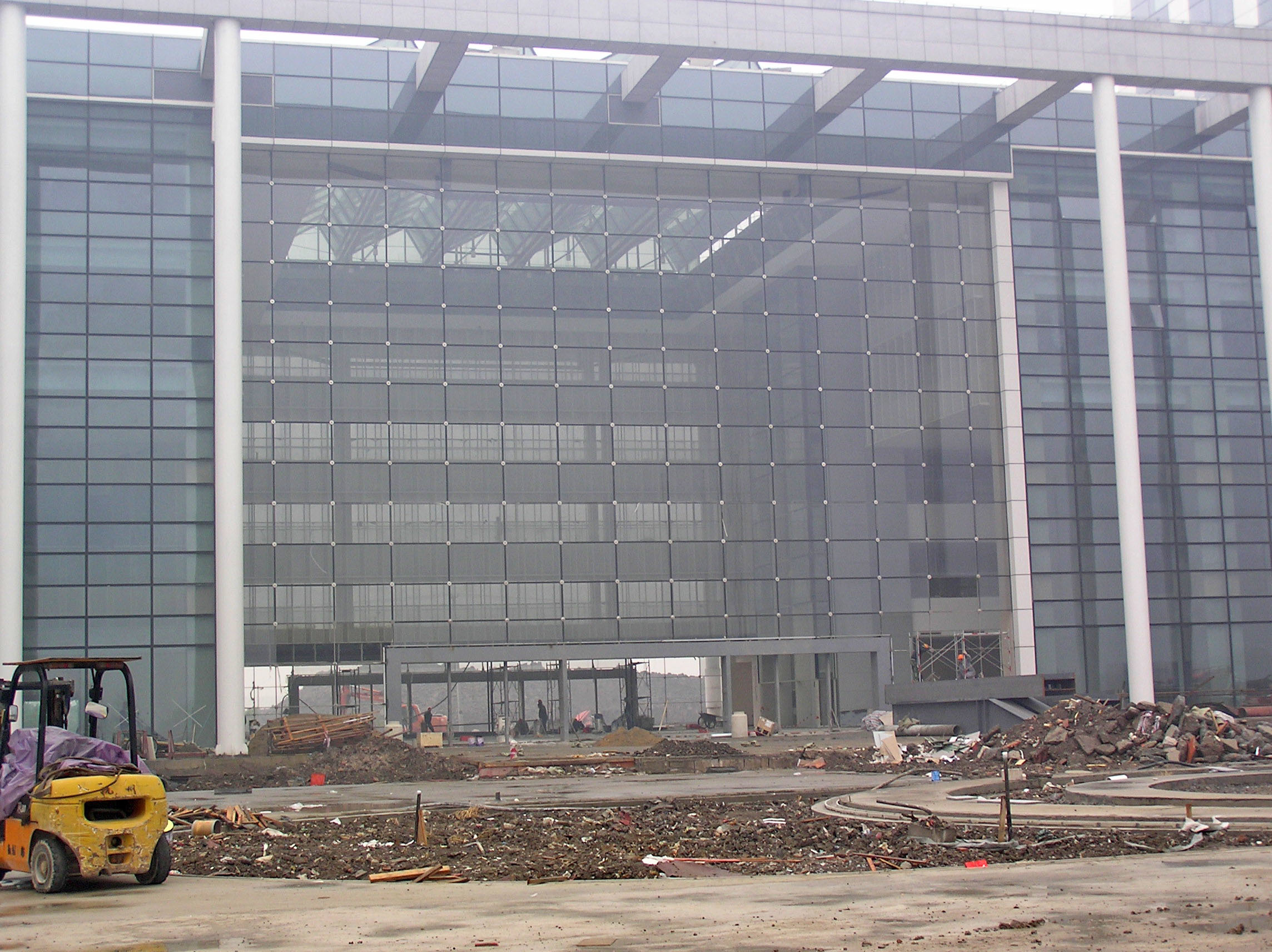 Large glass and steel structure under construction in gray and white industrial tones, conveying build and development